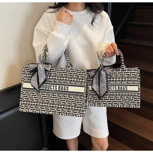 Detail of canvas tote bags in two sizes with geometric maze pattern and silk scarf handle
