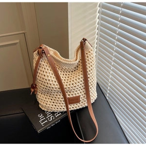 Détail de sac seau en maille beige ajourée avec bandoulière en cuir marron et logo