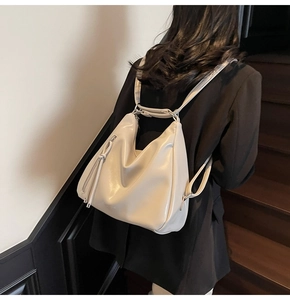 Detailed side view of beige soft leather backpack with stylish tassel zipper accents