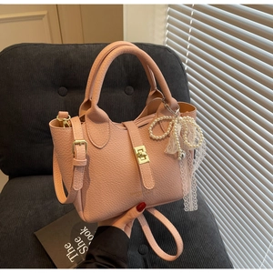 Pink lychee grain leather bucket bag with gold lock and pearl lace bow charm