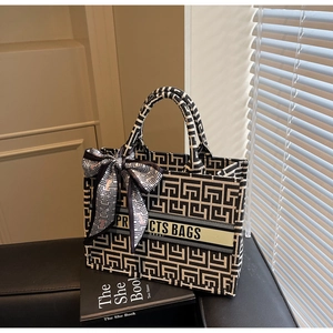 Detail of canvas tote bag with geometric pattern, ribbon handle, and text branding