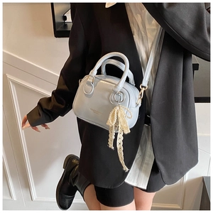 Dettaglio della mini borsa Boston azzurra con ciondolo a fiocco di perle e tracolla