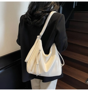Detail of a large cream hobo bag with fringe zipper showing soft faux leather texture