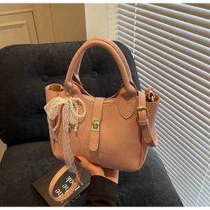 Detail of pink bucket bag featuring a lace bow, pearl charm, and golden twist lock