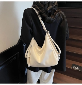 Close-up of cream leather shoulder bag on model showing soft texture and logo detail