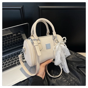 Detail of a beige knit Boston bag featuring a pearl lace bow and silver hardware