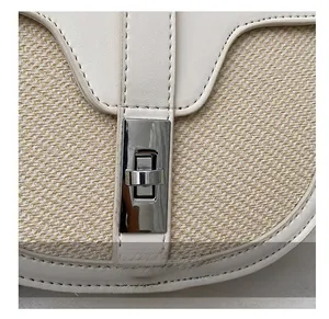 Detail of silver twist lock on a two-tone woven saddle bag with cream leather piping