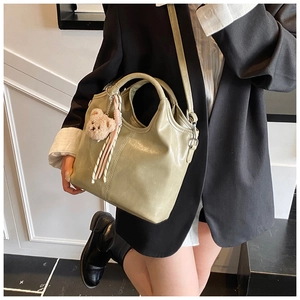Detail of sage green leather bucket bag with plush bear charm and detachable strap