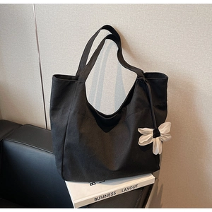 Detail of black canvas tote bag with a white mesh flower charm in a modern minimalist setting
