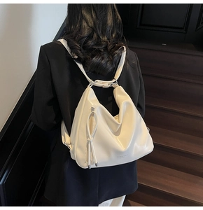 Detail of cream soft leather backpack featuring tassel zipper and minimalist text