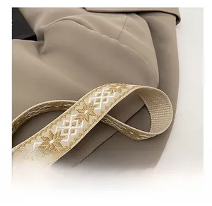 Close-up of geometric woven shoulder strap in beige and brown on a textured suit fabric