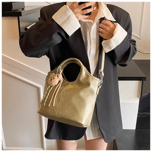 Detail of olive green bucket bag with plush bear charm and detachable shoulder strap