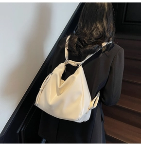 Detailed side view of a cream-white soft leather tote backpack on a model