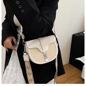 Detail of cream saddle bag with woven texture and geometric embroidered strap