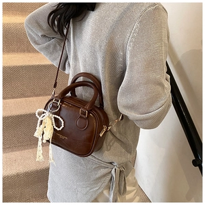 Dettaglio mini borsa Boston marrone retrò con ciondolo in pizzo e finiture dorate