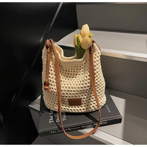 Détail du sac seau en maille beige avec bandoulière en cuir marron et patch logo