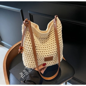 Détail du sac seau en tricot ajouré avec bandoulières en cuir marron et logo de marque