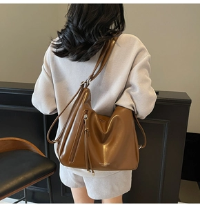 Detail view of deep brown leather backpack with long tassel zipper and side zipper accents