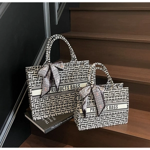 Detail view of large and small canvas tote bags with geometric patterns on wooden stairs