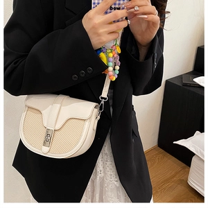 Contrast saddle crossbody bag in cream leather and woven straw detail on female model