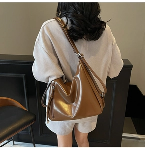 Detailed view of brown leather hobo bag showing zipper details and adjustable shoulder strap
