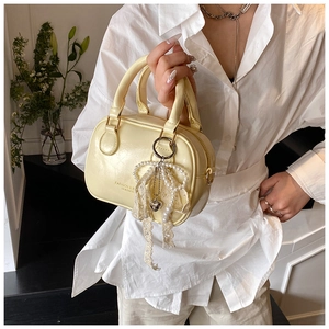 Dettaglio borsa in pelle giallo crema con ciondolo a fiocco in pizzo e perle e zip