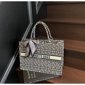 Close-up of geometric canvas tote bag with ribbon detail on a wooden staircase
