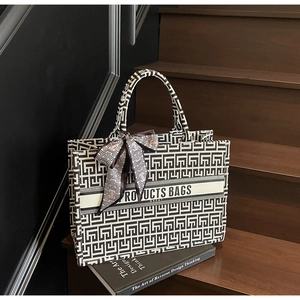 Detail of canvas tote bag featuring geometric maze patterns and decorative ribbon bow