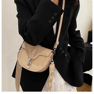 Detail of contrast saddle bag with woven texture and embroidered guitar strap for women