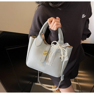 Close-up of light blue lychee pattern bucket bag with pearl lace bow and gold twist lock