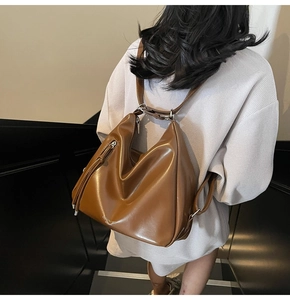 Detailed view of a brown leather hobo bag with adjustable strap and silver metal hardware