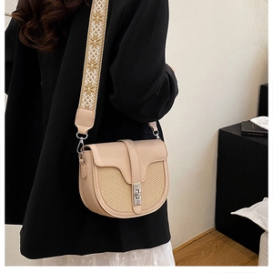 Detail view of contrast stitch saddle bag with woven texture and jacquard wide strap