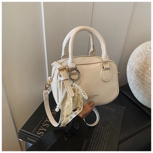 Dettaglio elegante borsa Boston crema in similpelle con ciondolo di perle e pizzo