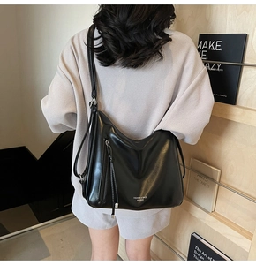 Close-up of black leather tote bag featuring side zipper pocket and long drawstring detail