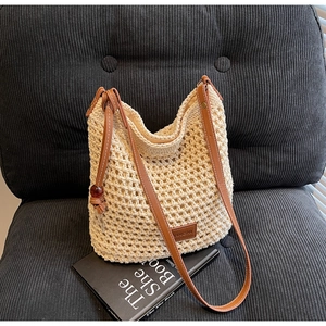 Détail de la texture tissée et de la bandoulière en cuir brun du sac seau blanc cassé