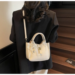 Detail of lychee pattern leather bucket bag with lace bow and pearl pendant charm