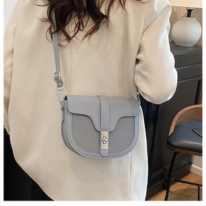 Detail of light blue saddle bag featuring grey plaid mesh and silver metal twist lock