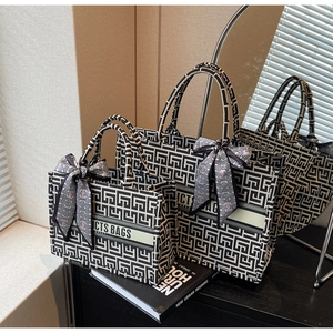 Detail of canvas tote bags with geometric pattern, ribbon branding and silk scarf handle