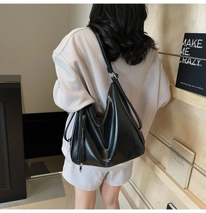 Detail view of a black soft leather hobo tote bag worn as a shoulder bag on a model