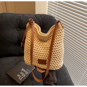Détail d'un sac seau au crochet beige avec bandoulière en cuir brun et étiquette