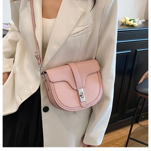 Detail of pink saddle bag featuring woven texture flap and silver swivel lock closure