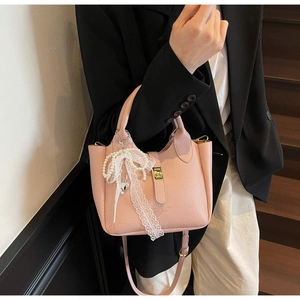 Close-up of pink bucket bag with litchi texture and elegant pearl lace bow charm