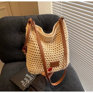 Gros plan détaillé du sac seau en maille crochet beige avec poignées en cuir marron