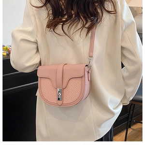 Pink matte leather saddle bag with silver twist lock on a white blazer model