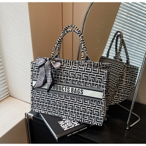 Detail of canvas tote bag with black and white geometric pattern and silk scarf handle