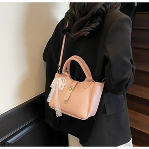 Pink lychee grain leather bucket bag with gold lock and delicate pearl lace charm detail