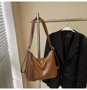 Detail of brown faux leather shoulder bag with vertical zipper tassel and fashion logo