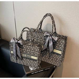 Detail of two geometric woven tote bags with decorative scarves on a leather sofa