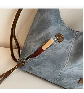 Close-up of front zipper pocket on denim tote bag showing lipstick for storage capacity