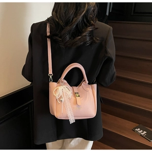 Pink lychee texture bucket bag featuring gold clasp and a delicate lace pearl bow charm